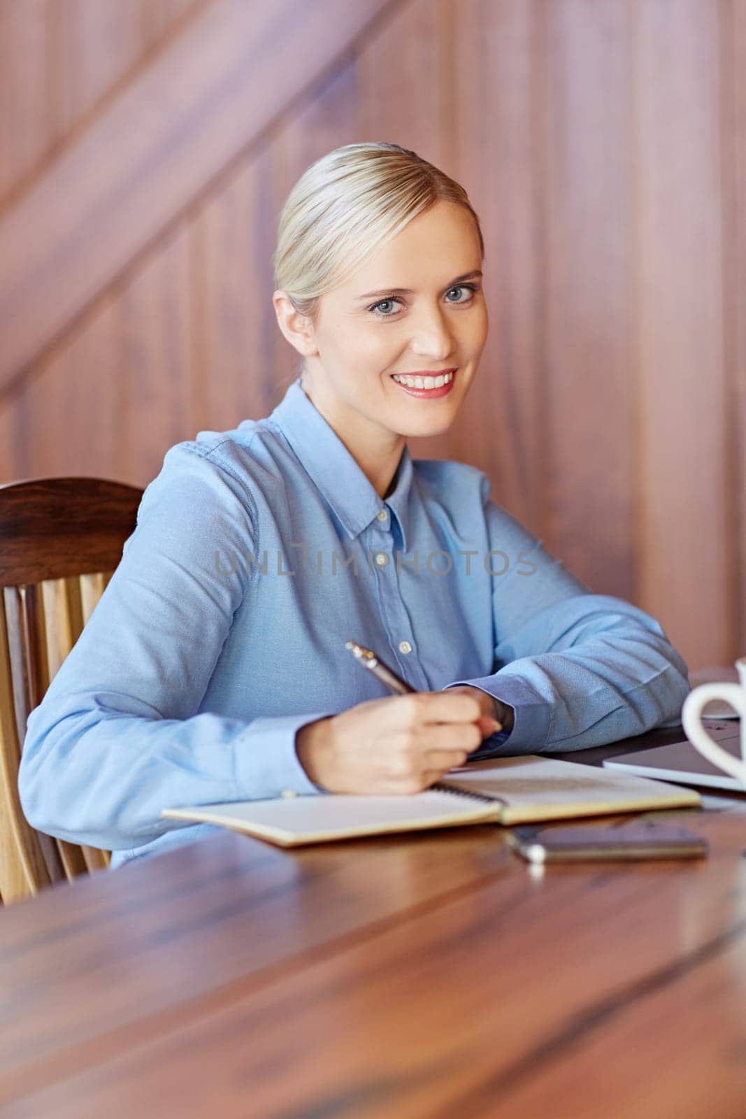 A young businesswoman taking notes in wooden office
