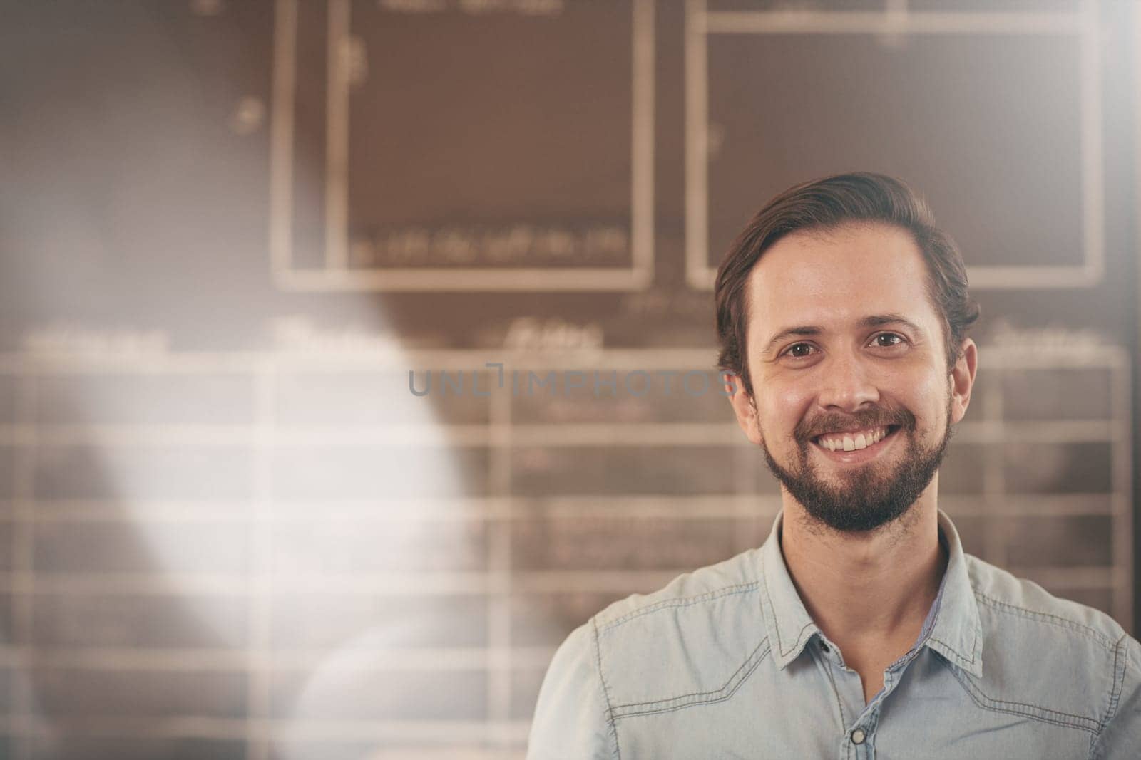 Head and shoulders portrait of a handsome craftsman and designer in his studio smiling at the camera