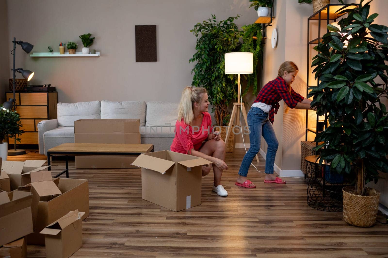 A loving mother and her excited daughter enjoy the fun of unpacking their boxes in their new cozy living space