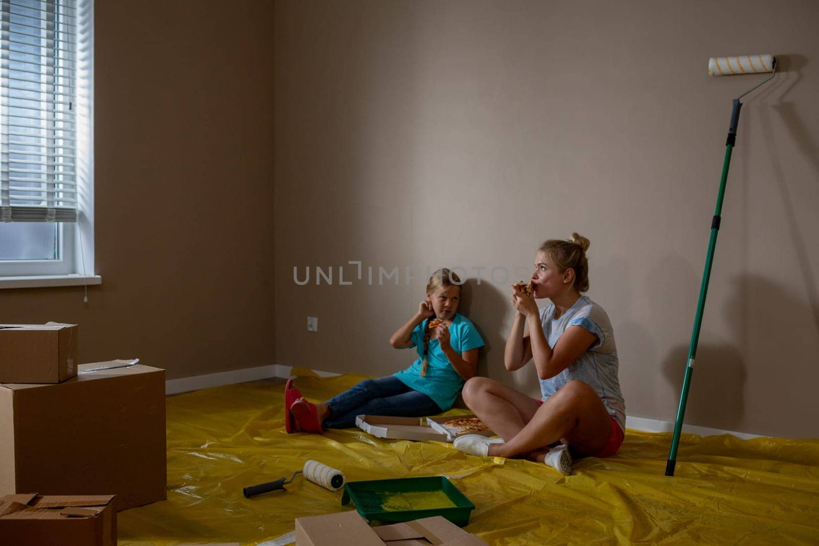 Two cheerful little girls are happily enjoying snacks together in a newly painted, vibrant living space