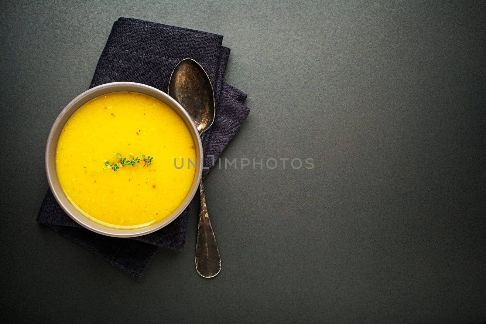 Healthy vegetable cream soup with herbs on dark background Top view