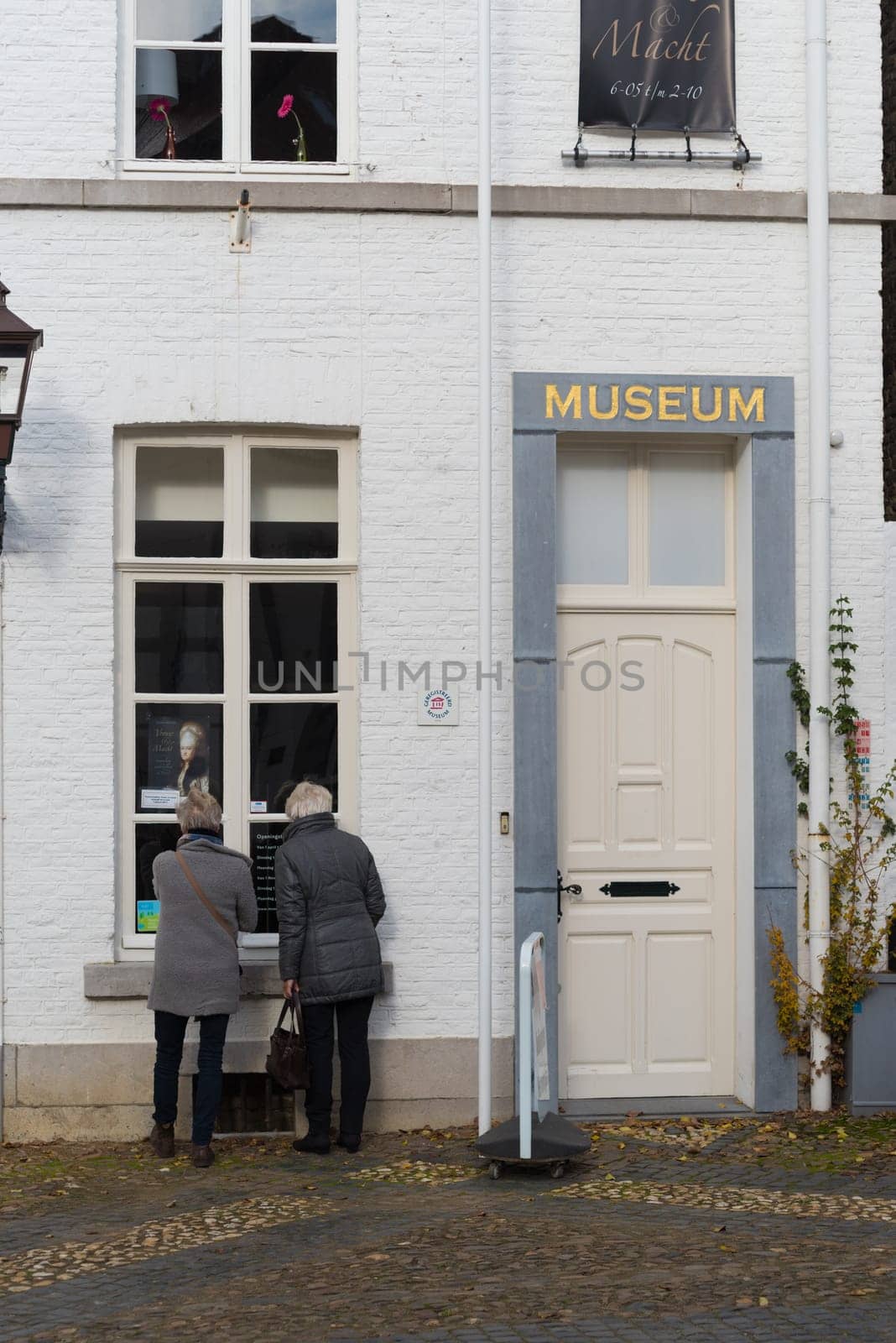 THORN, NETHERLANDS - NOVEMBER 6, 2016: Two unknown elderly women looking through a museum window in the white village of Thorn