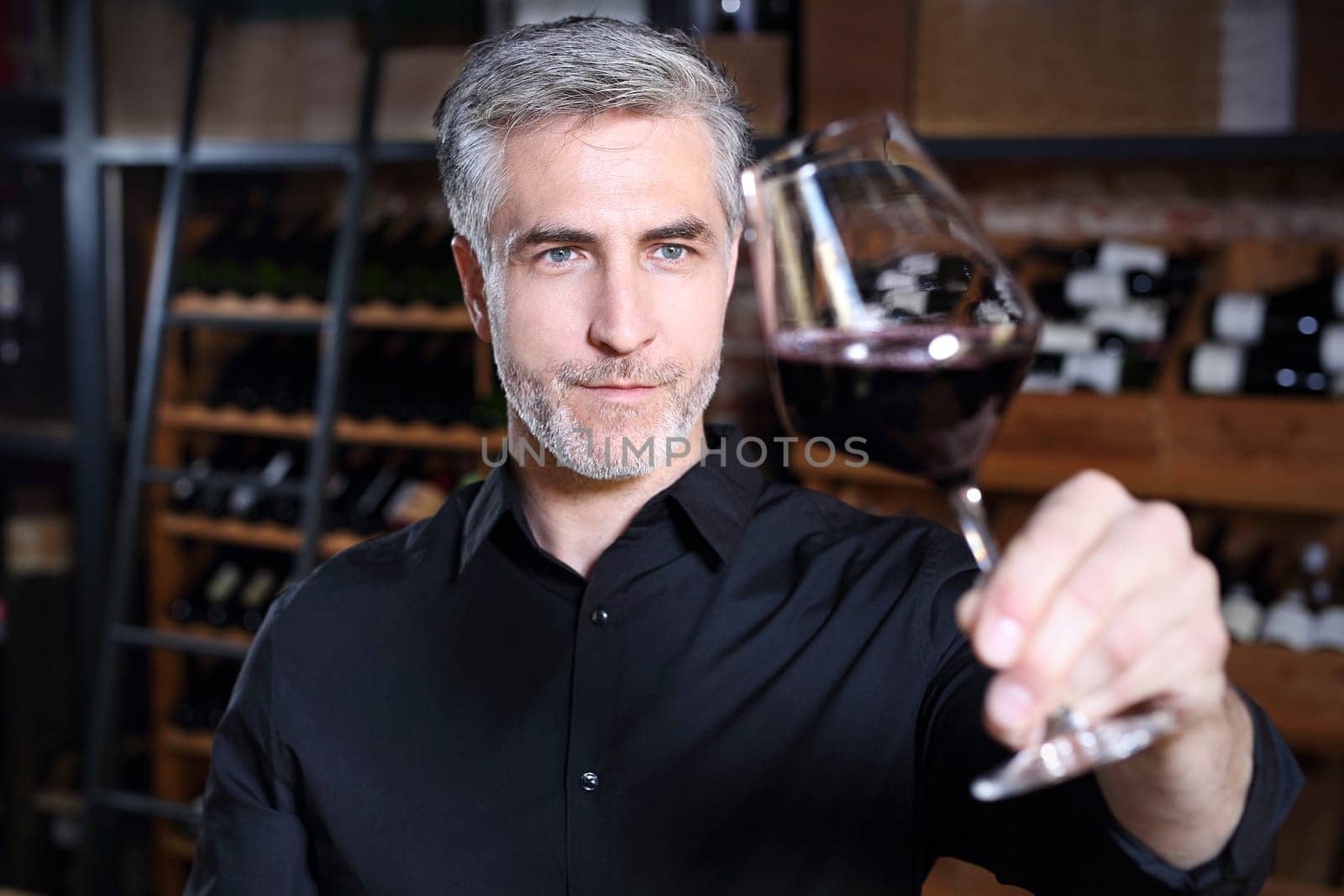 Man poured red wine into a glass. Sommelier selects wine.