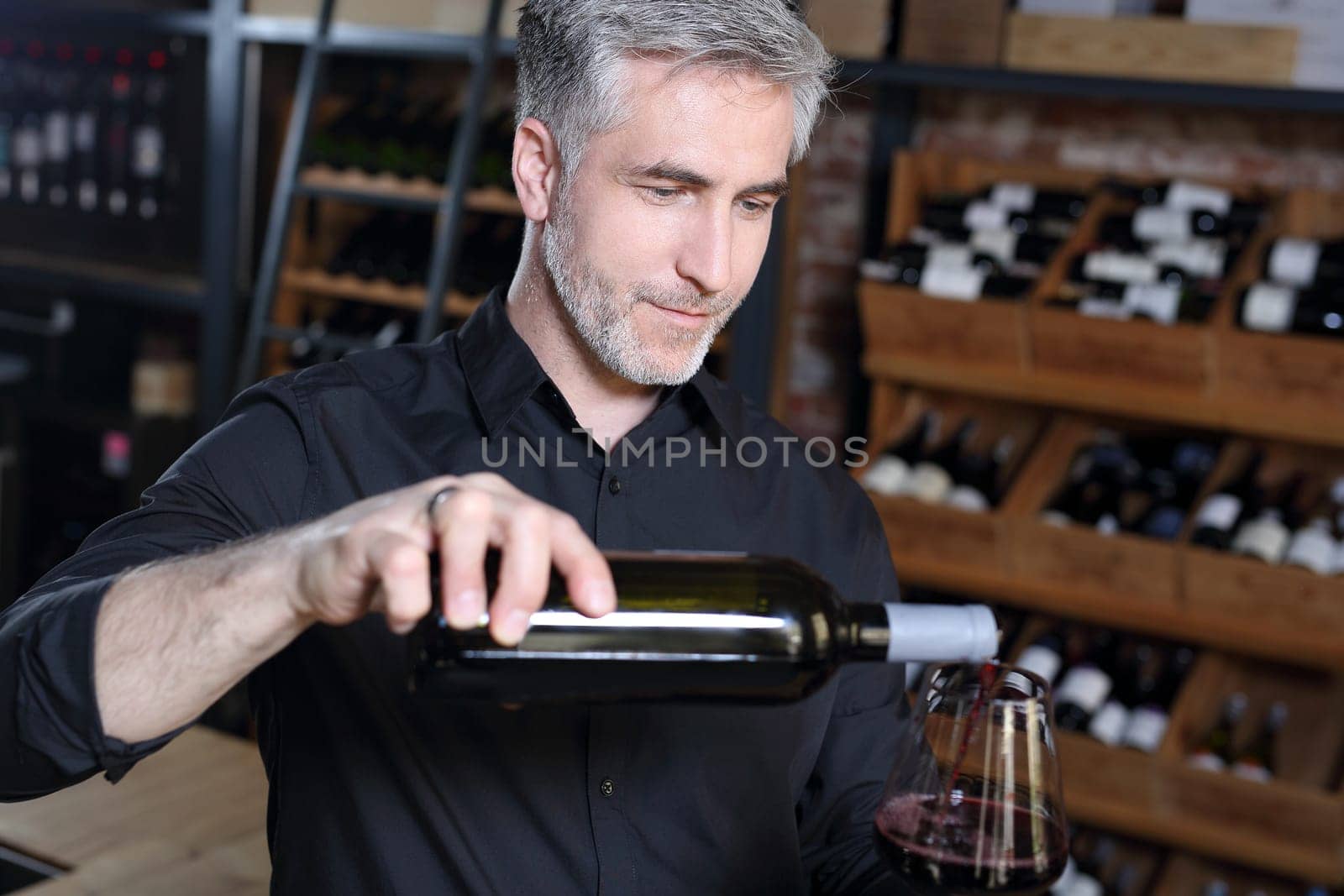 Man poured red wine into a glass. Sommelier selects wine.