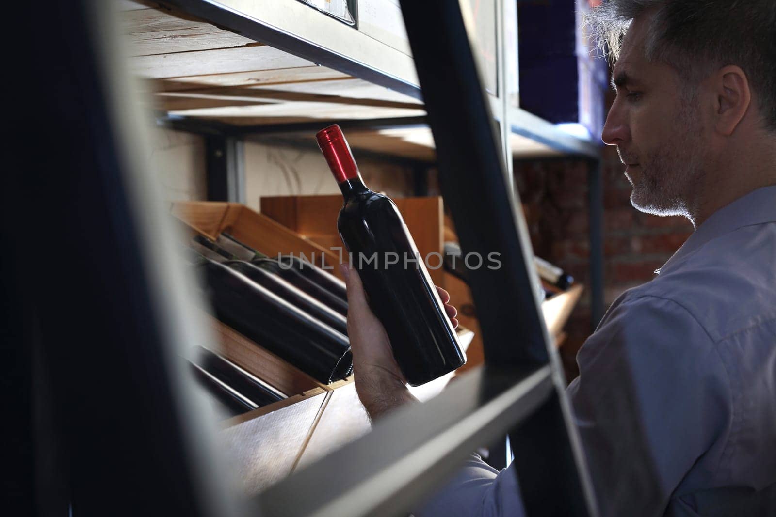 Wine. Man chooses a bottle of wine. Wine cellar