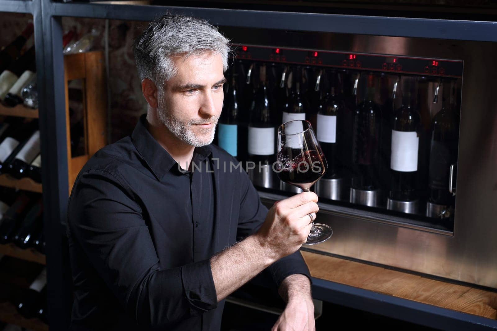 Man poured red wine into a glass. Sommelier selects wine.