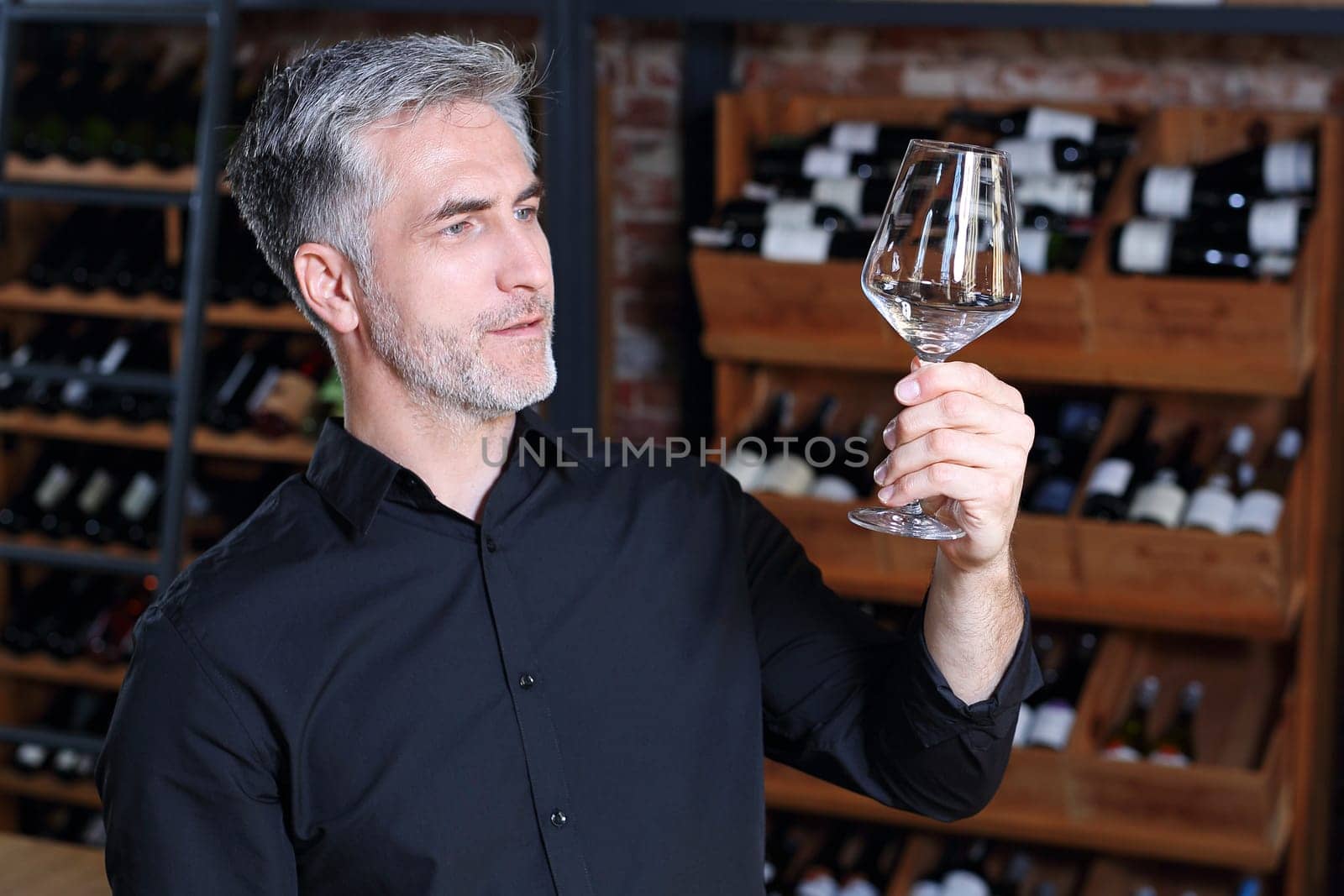 A handsome bartender polishes a glass of wine glasses.