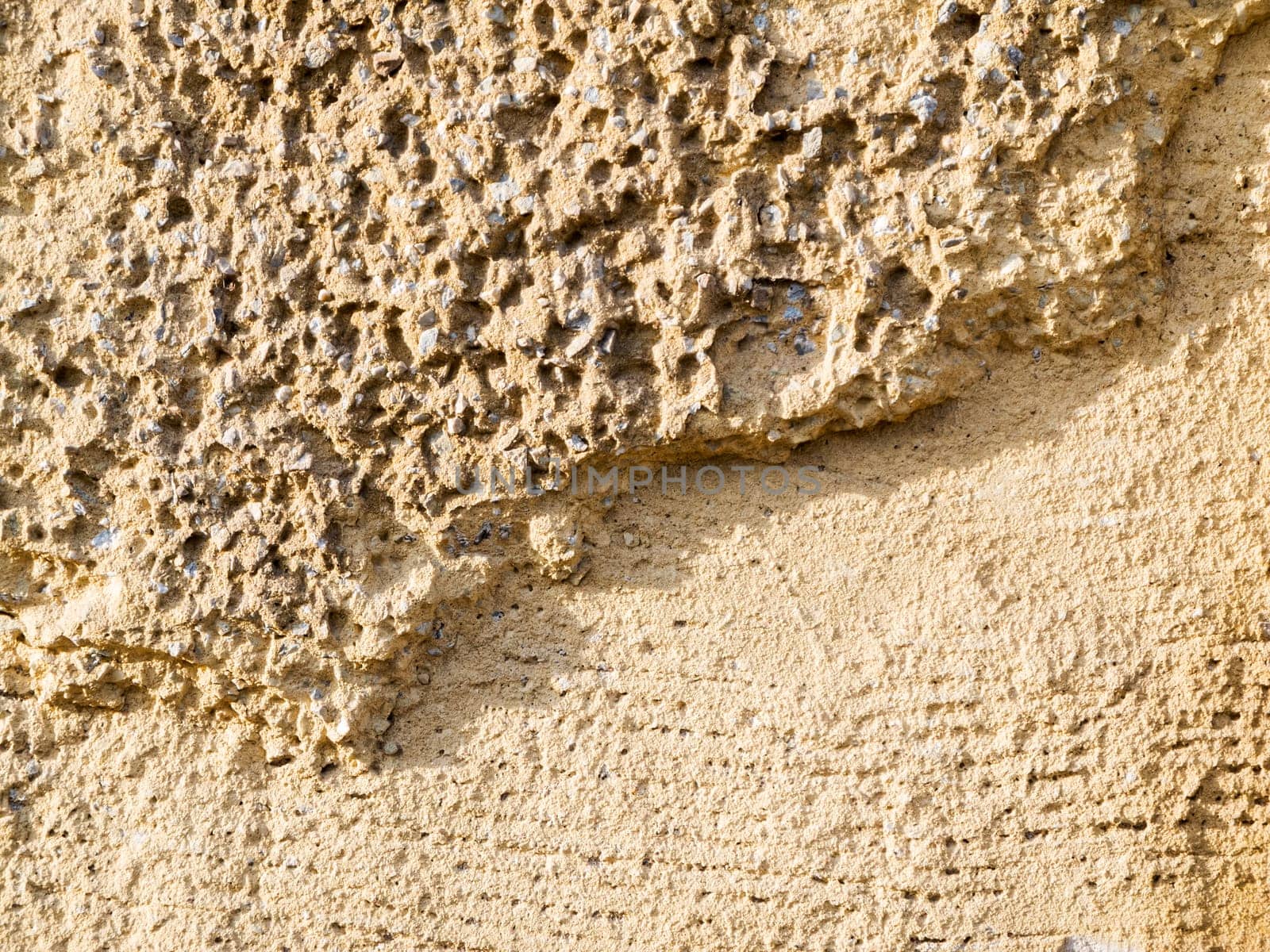 Format-filling view of old masonry with partially detached rough plaster and clinker bricks.