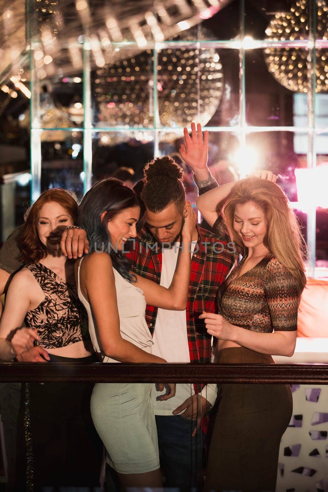 People are dancing in a nightclub. One couple are being flirtacious while people dance around them.
