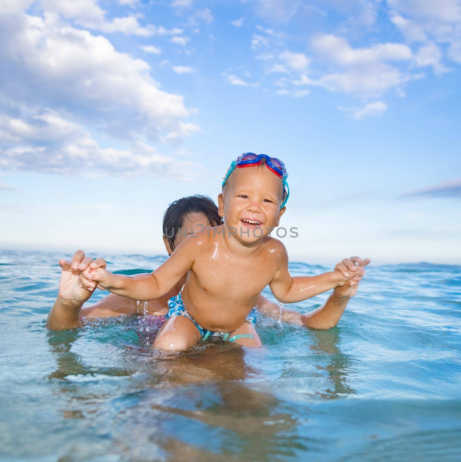 Cute boy with mother plays in a sea