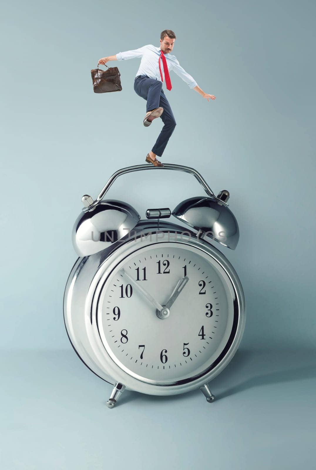 Businessman balancing over alarm clock. Collage about tardiness and lack of time. concept of business acceleration