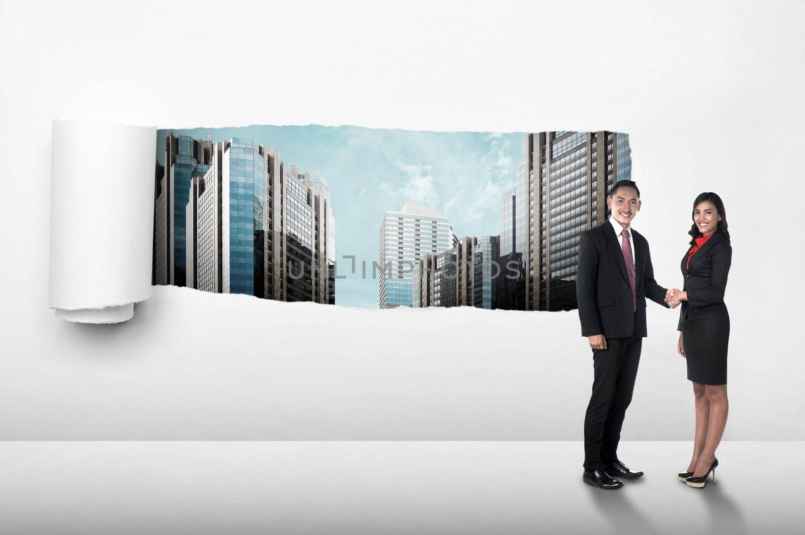 Asian business people shaking hand over paper tear background