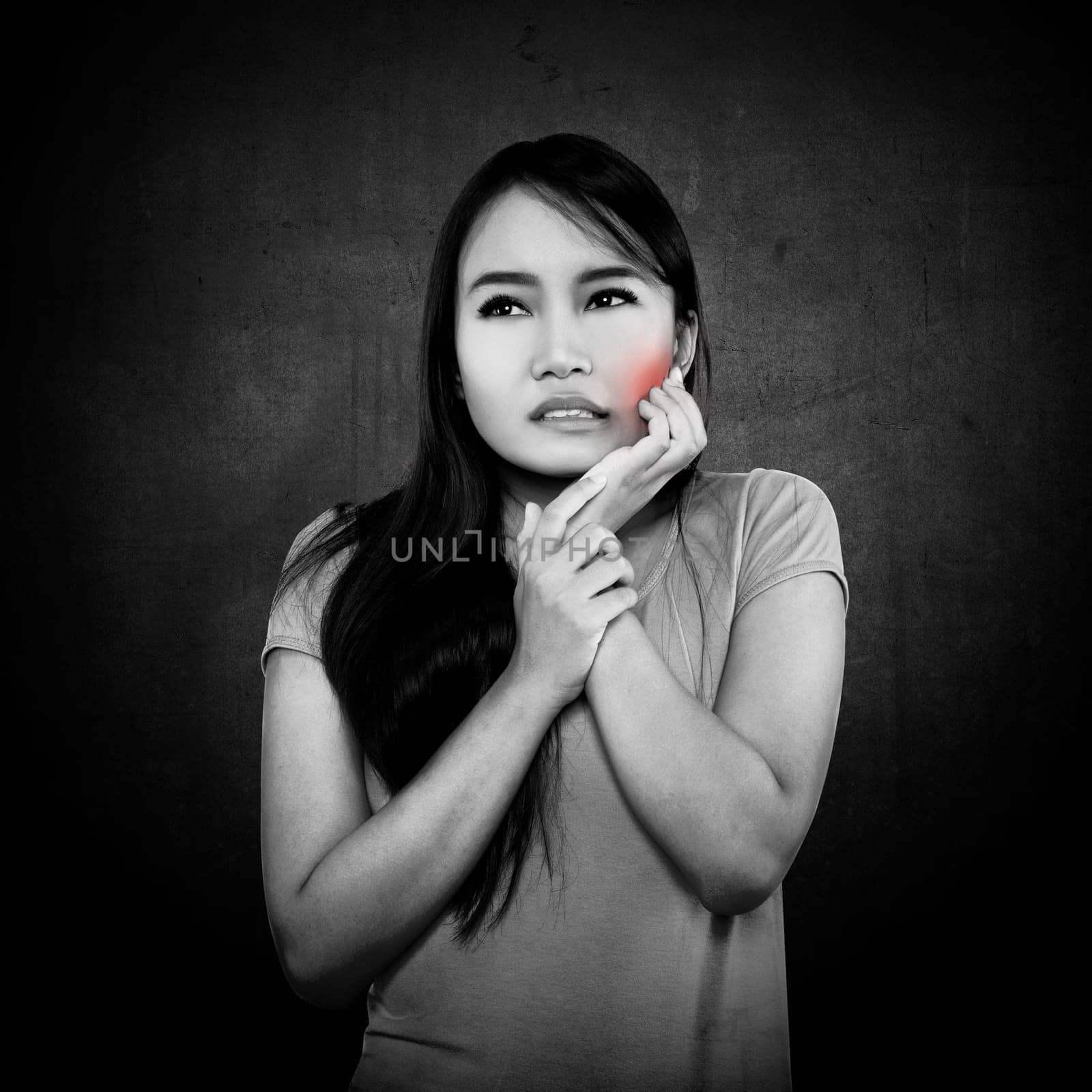 Woman pressing her cheek with a painful expression as if she's having a terrible toothache.