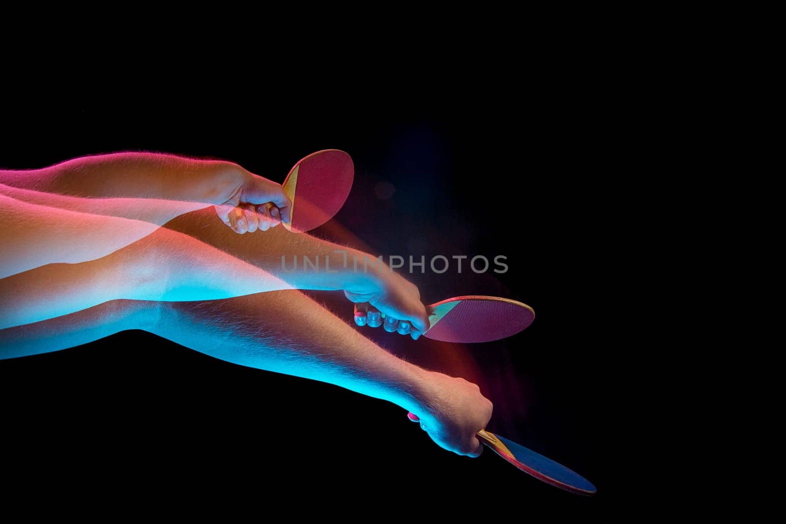 The male hands of table tennis player close up on black background. Stroboscope shooting technique