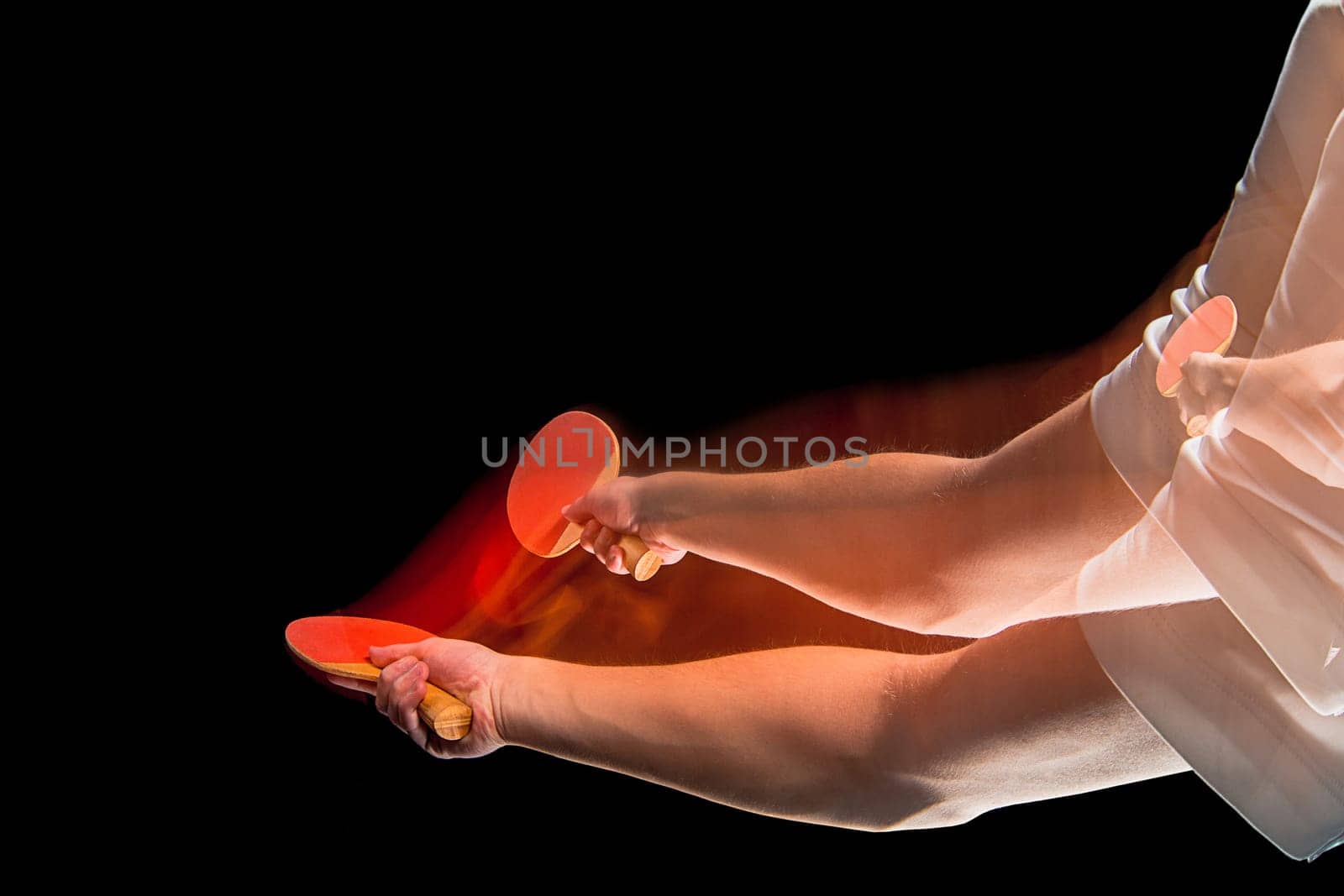 The male hands of table tennis player close up on black background. Stroboscope shooting technique