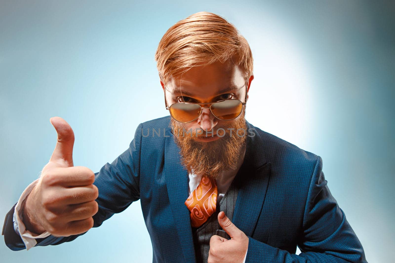 Portrait of a business man presenting something on blue background. Studio shot.