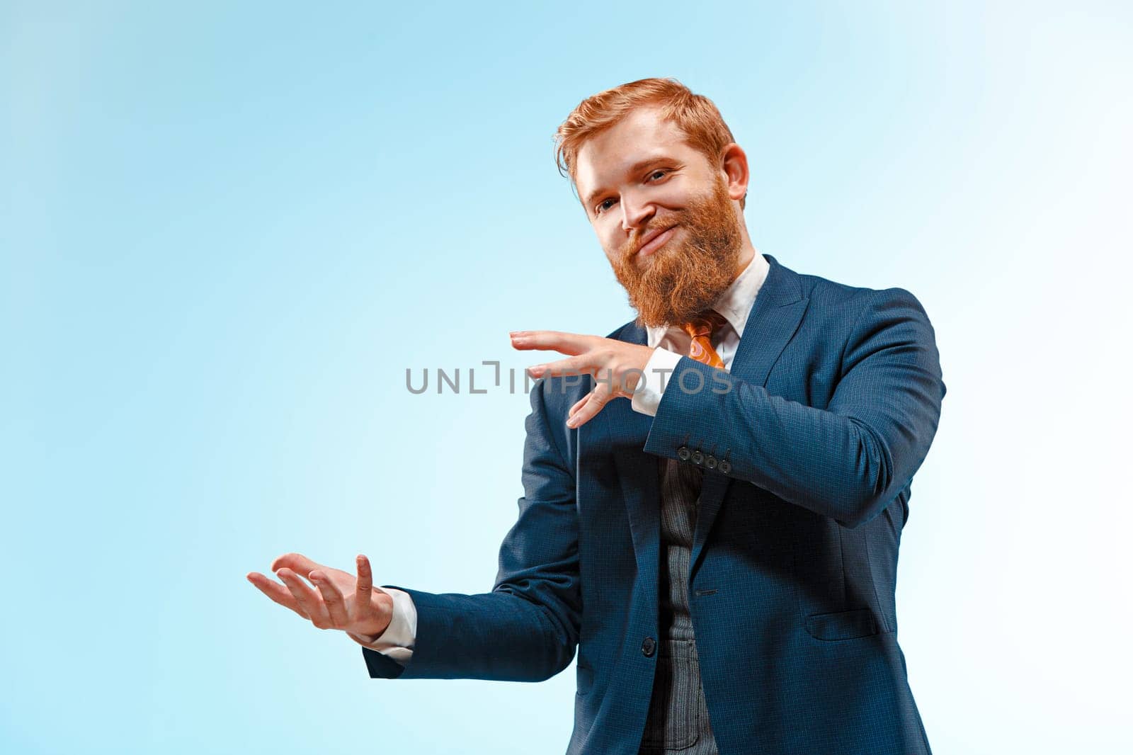 Portrait of a business man presenting something on blue background. Studio shot.
