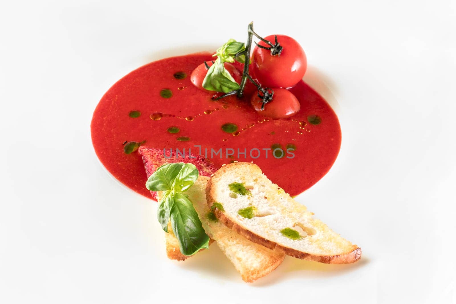 Tomato soup with toast bread in a large white plate