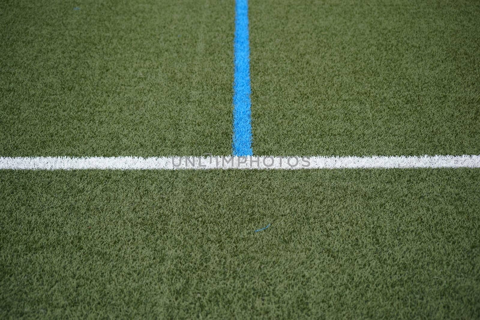 The green lawn of a football field with the sideline and the center line.