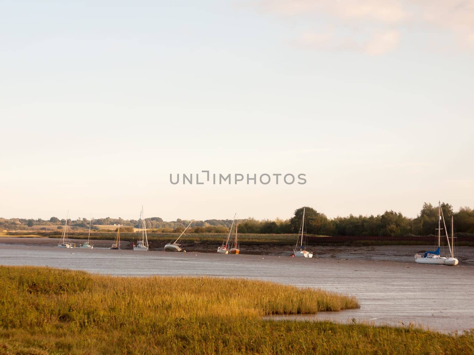 sunset scene over river through country with moored boats and clear sky  England  Essex