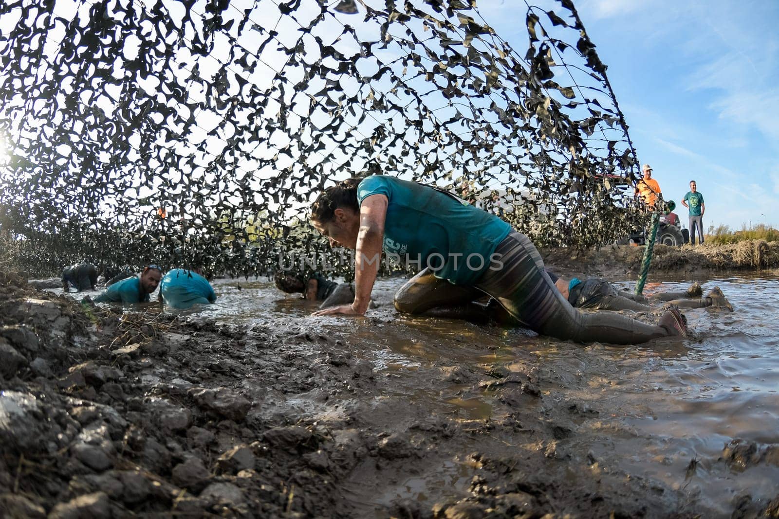 ESTARREJA, PORTUGAL - SEPTEMBER 23: Athletes crawling through mud at the Biorace on september 23, 2017 in Estarreja, Portugal.