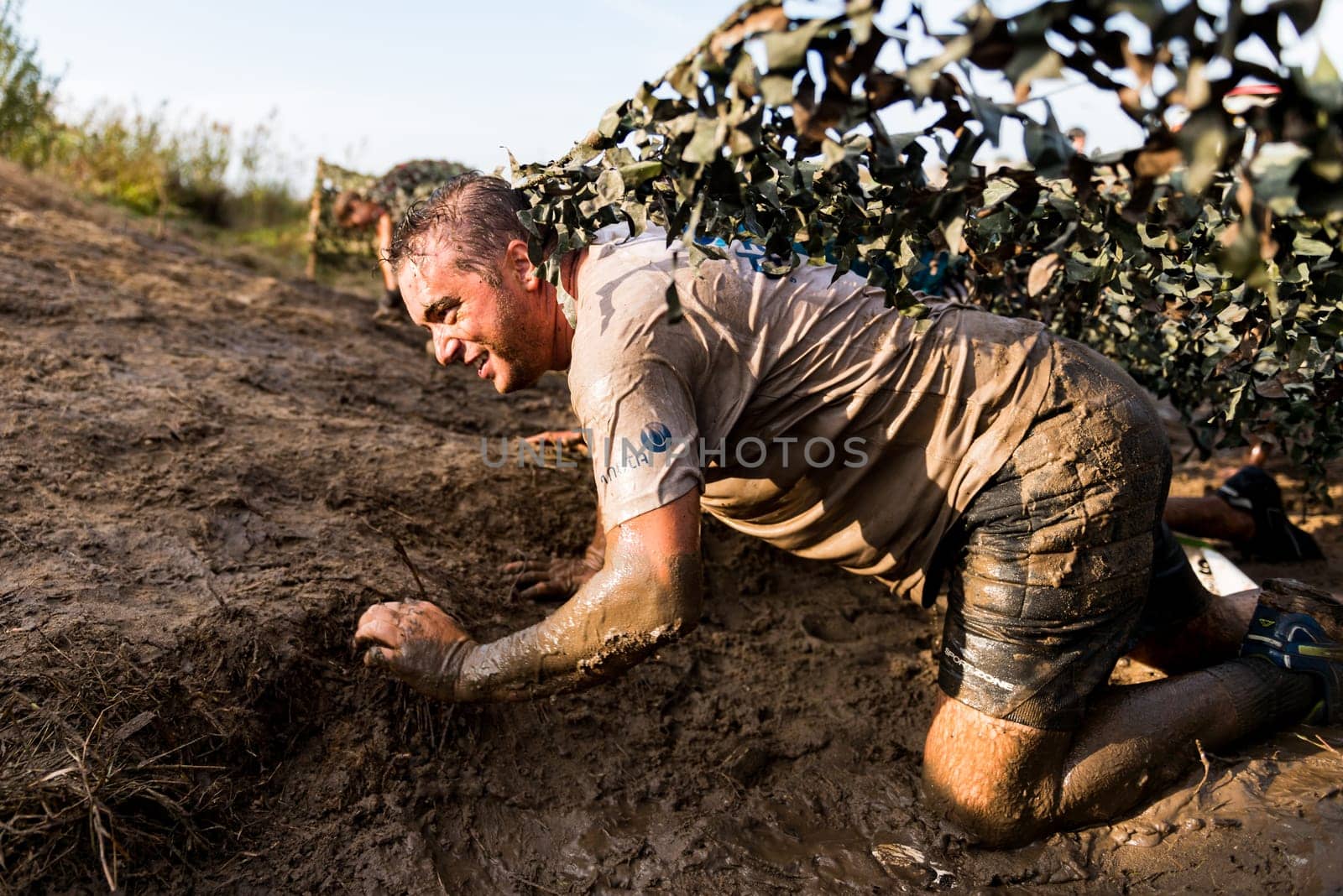 ESTARREJA, PORTUGAL - SEPTEMBER 23: Athletes crawling through mud at the Biorace on september 23, 2017 in Estarreja, Portugal.