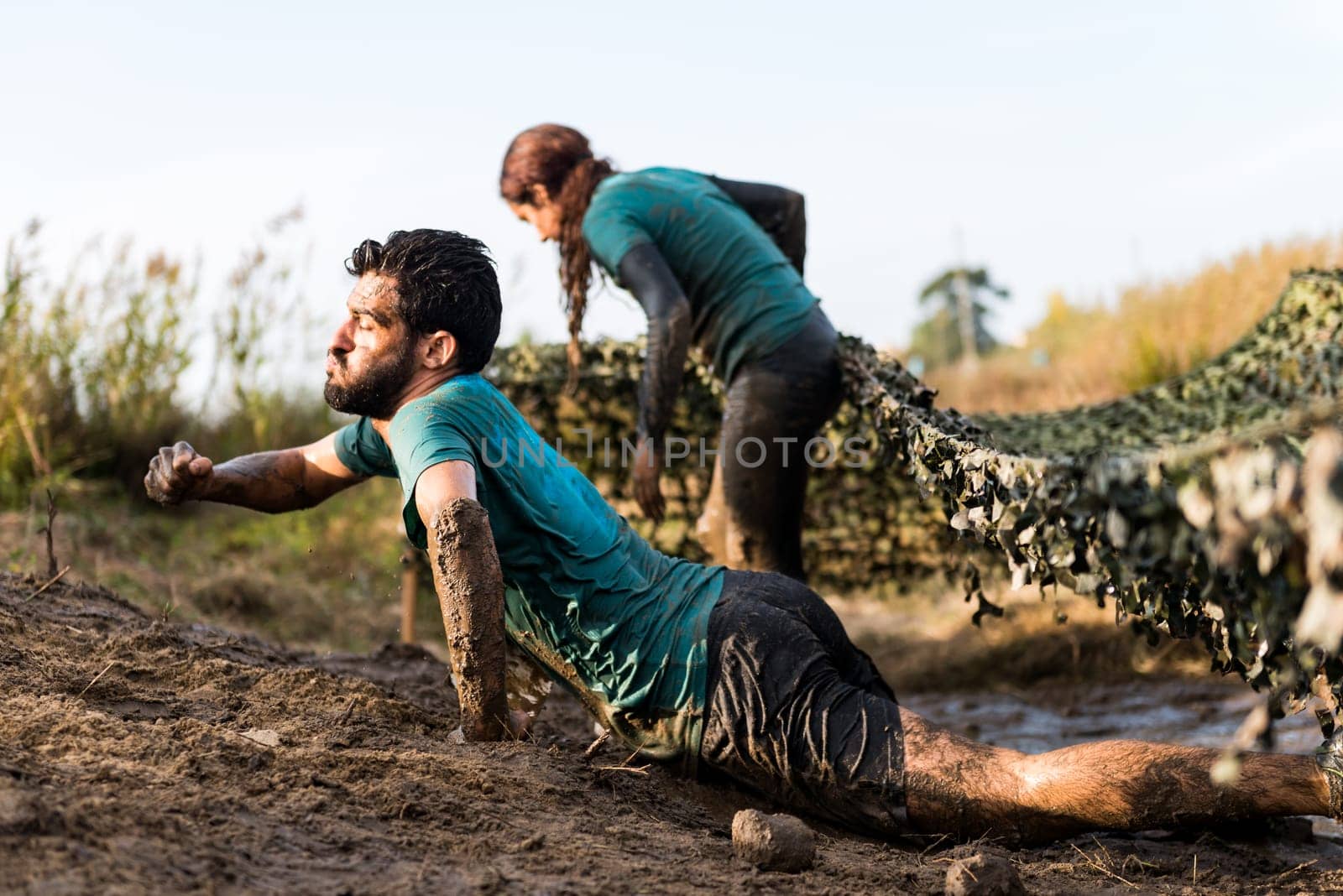 ESTARREJA, PORTUGAL - SEPTEMBER 23: Athletes crawling through mud at the Biorace on september 23, 2017 in Estarreja, Portugal.