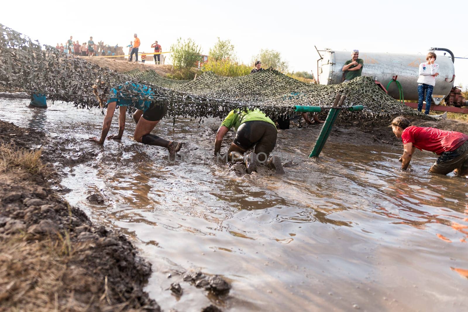 ESTARREJA, PORTUGAL - SEPTEMBER 23: Athletes crawling through mud at the Biorace on september 23, 2017 in Estarreja, Portugal.
