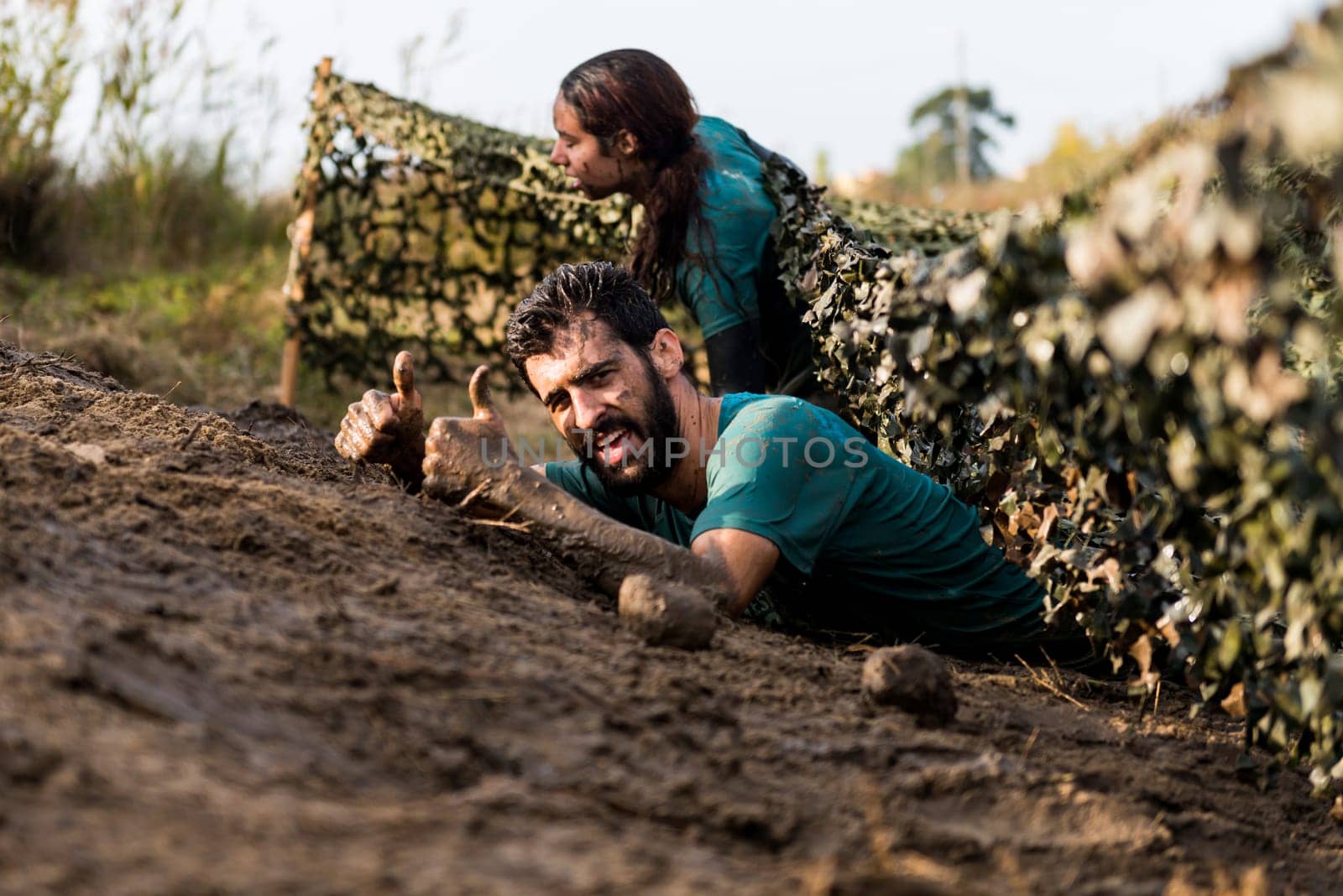 ESTARREJA, PORTUGAL - SEPTEMBER 23: Athletes crawling through mud at the Biorace on september 23, 2017 in Estarreja, Portugal.