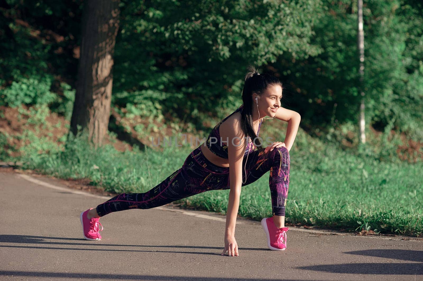 Concept of sport and lifestyle - young woman doing warm-up, smiling, outdoors.