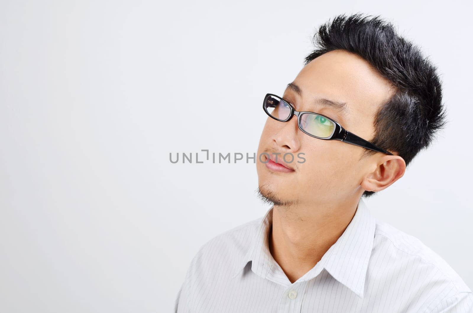 Portrait of Asian business man thinking and looking at side, standing isolated on plain background.