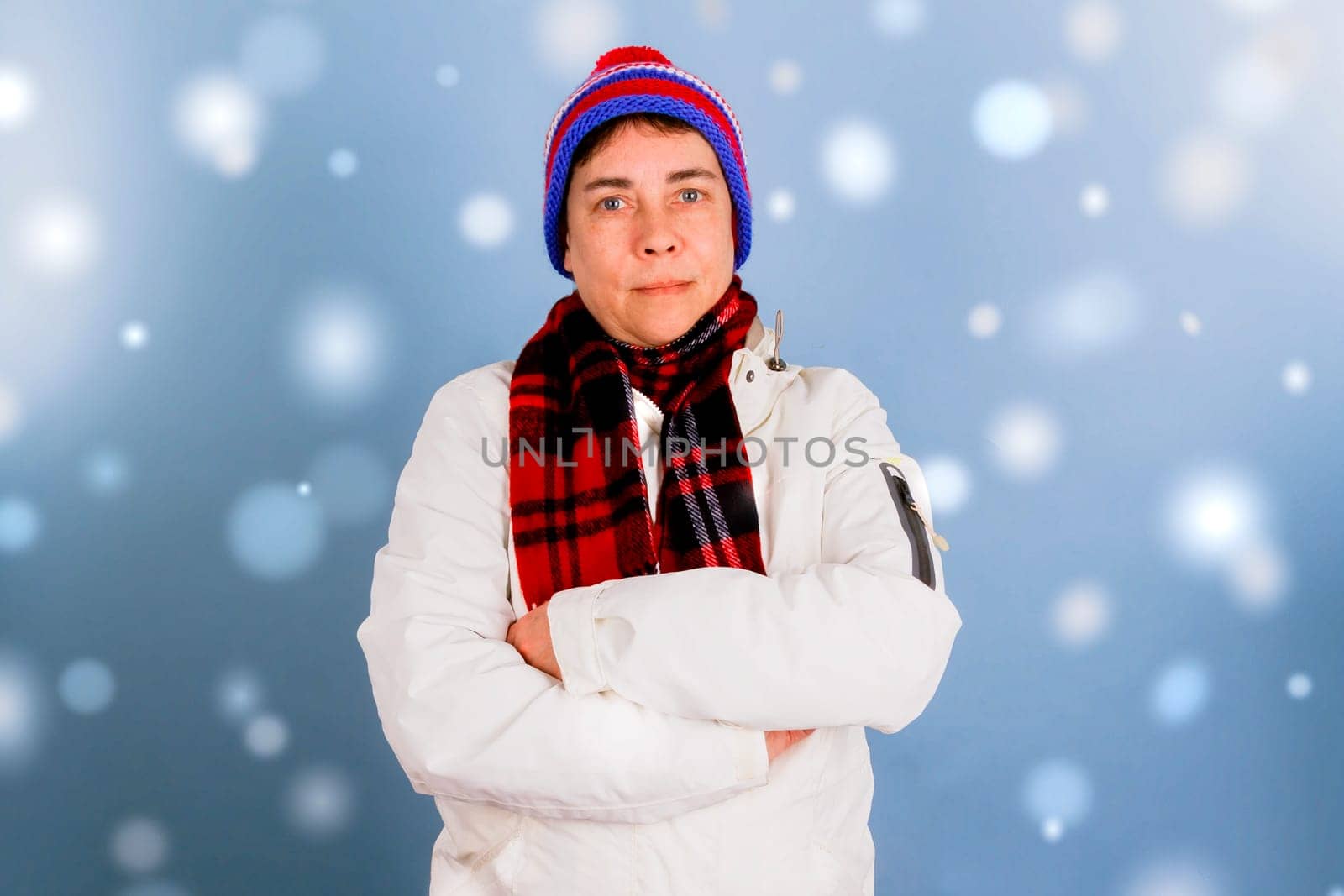 Woman with crossed arms in winter clothes with snowflakes