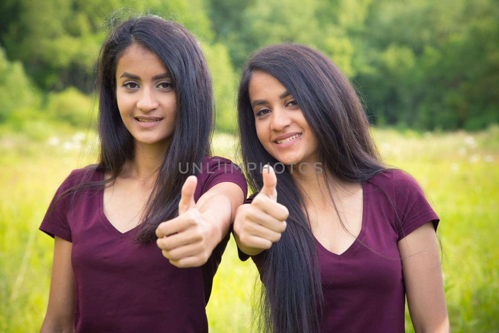 Twins keep thumbs up - outdoor view in summer
