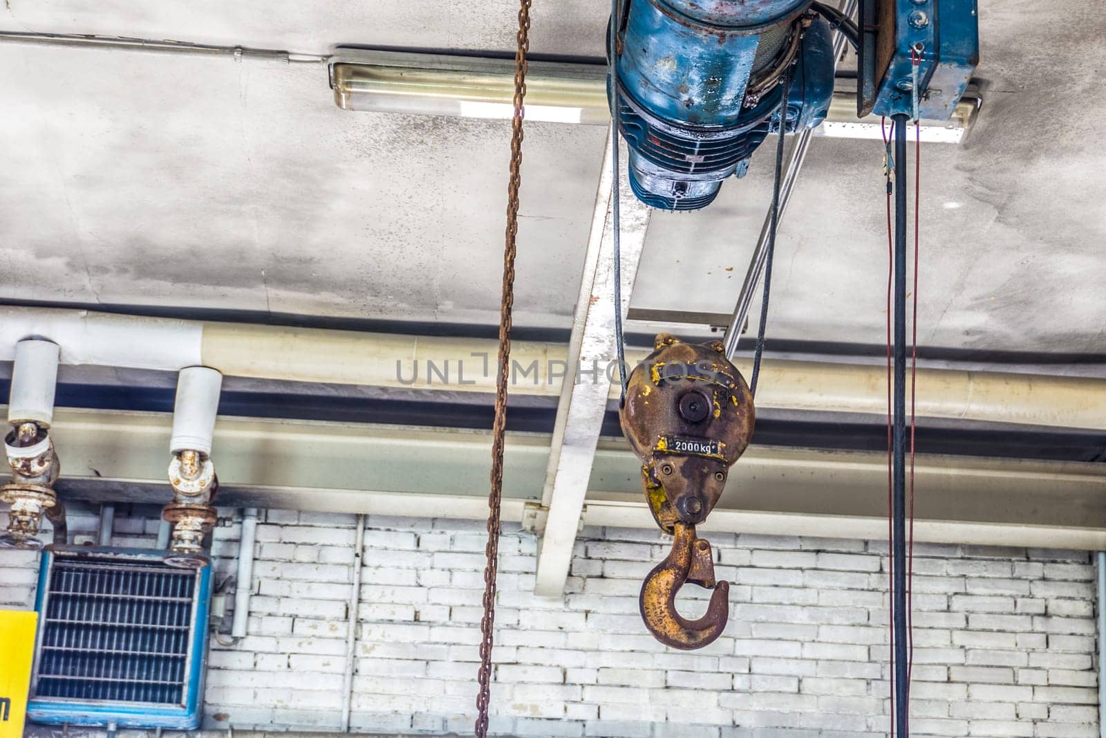 Old heavy wire rope hoist hanging in detail on a ceiling.