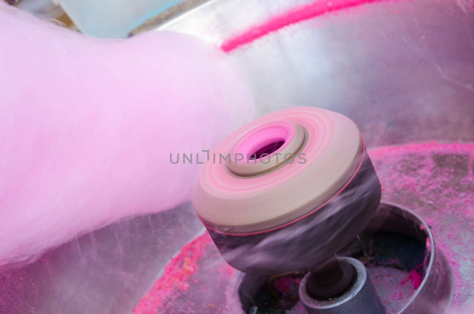 Hand rolling cotton candy in candy floss machine.