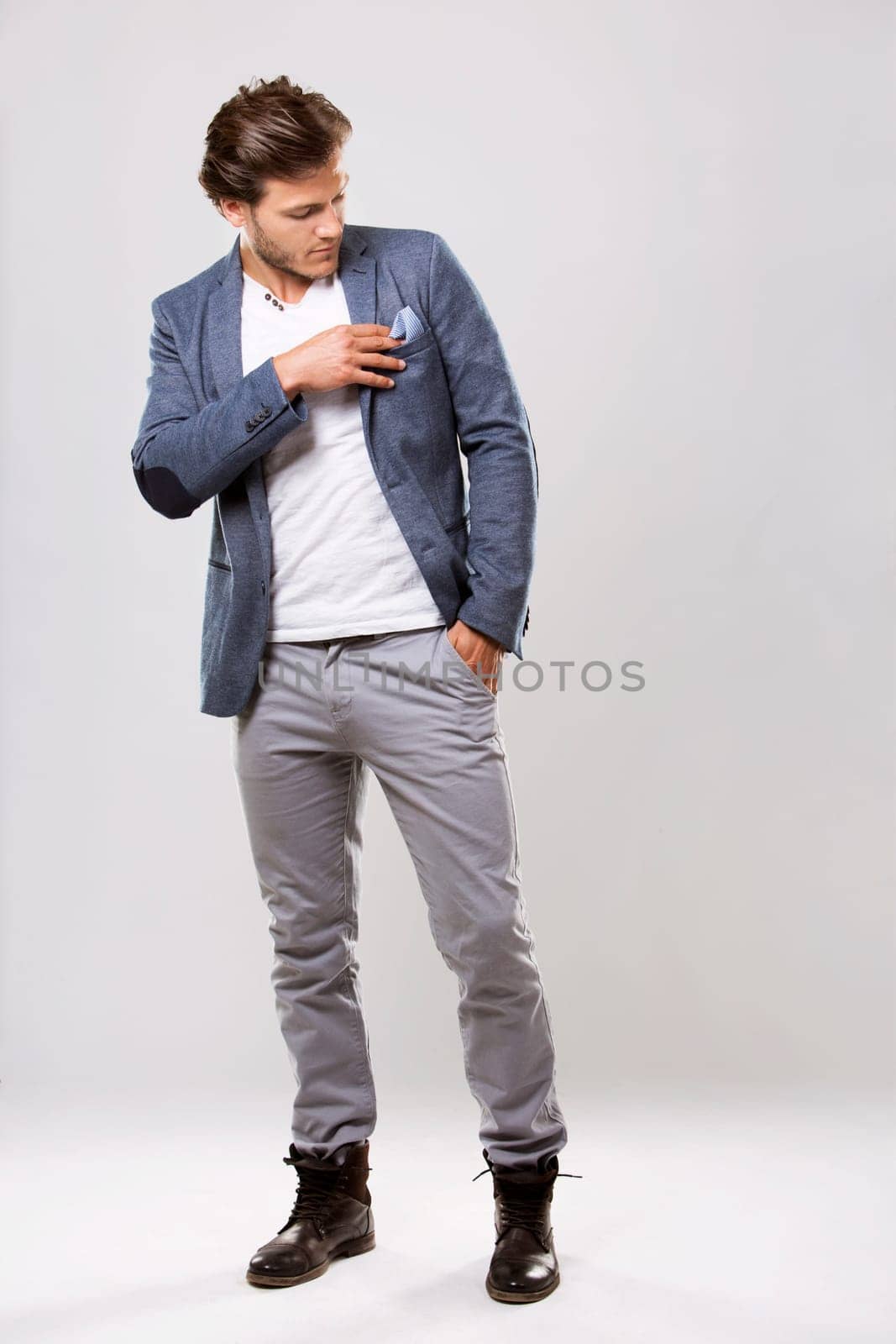Fashion portrait of a handsome man with trendy hairstyle in a stylish jacket on light background