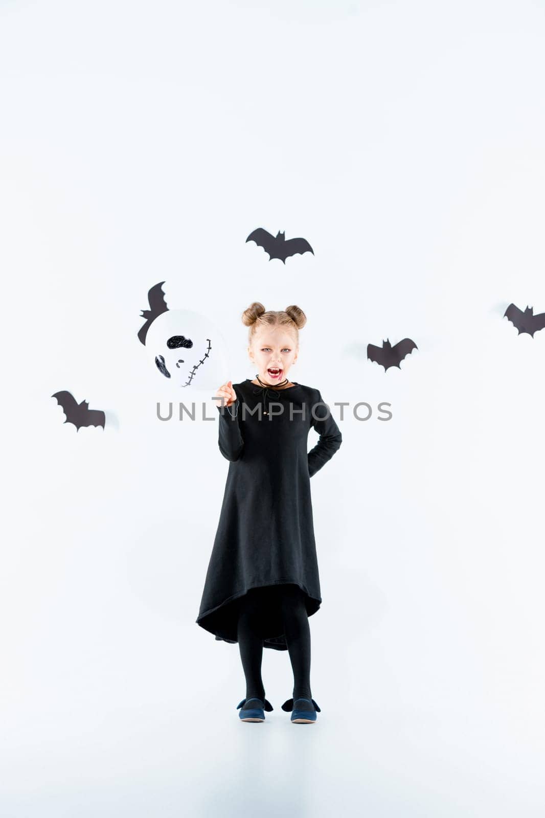 Little girl witch in black long dress and magical accessories. Halloween, the studio evening.