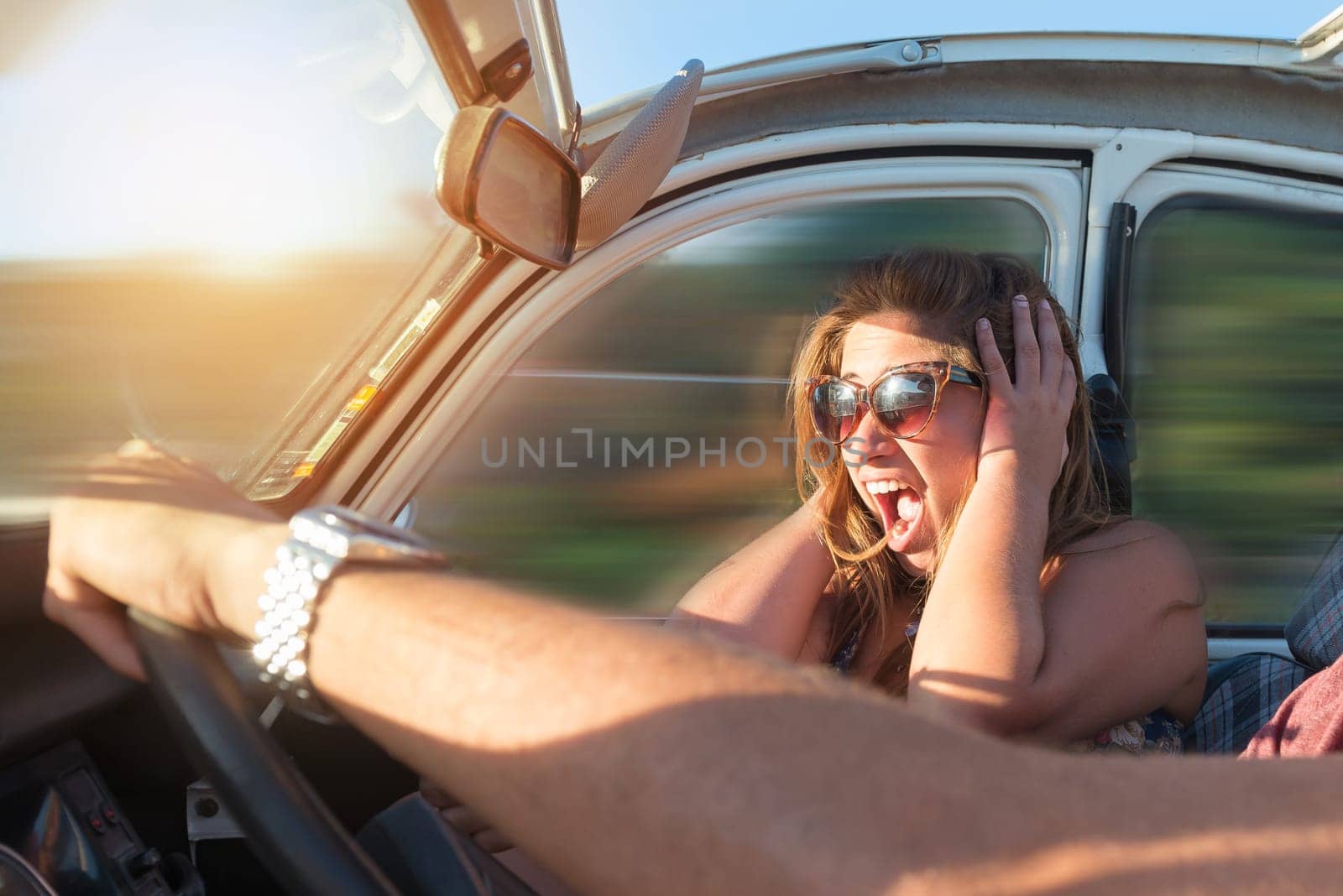 Couple in a car at sunset, with male driving fast and girl scared, screaming and praying.