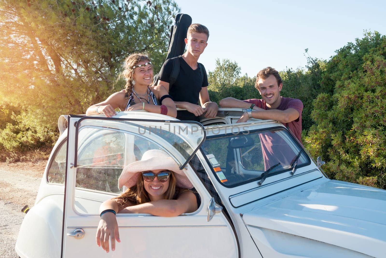 Group of happy people near a car in summertime, retro style.