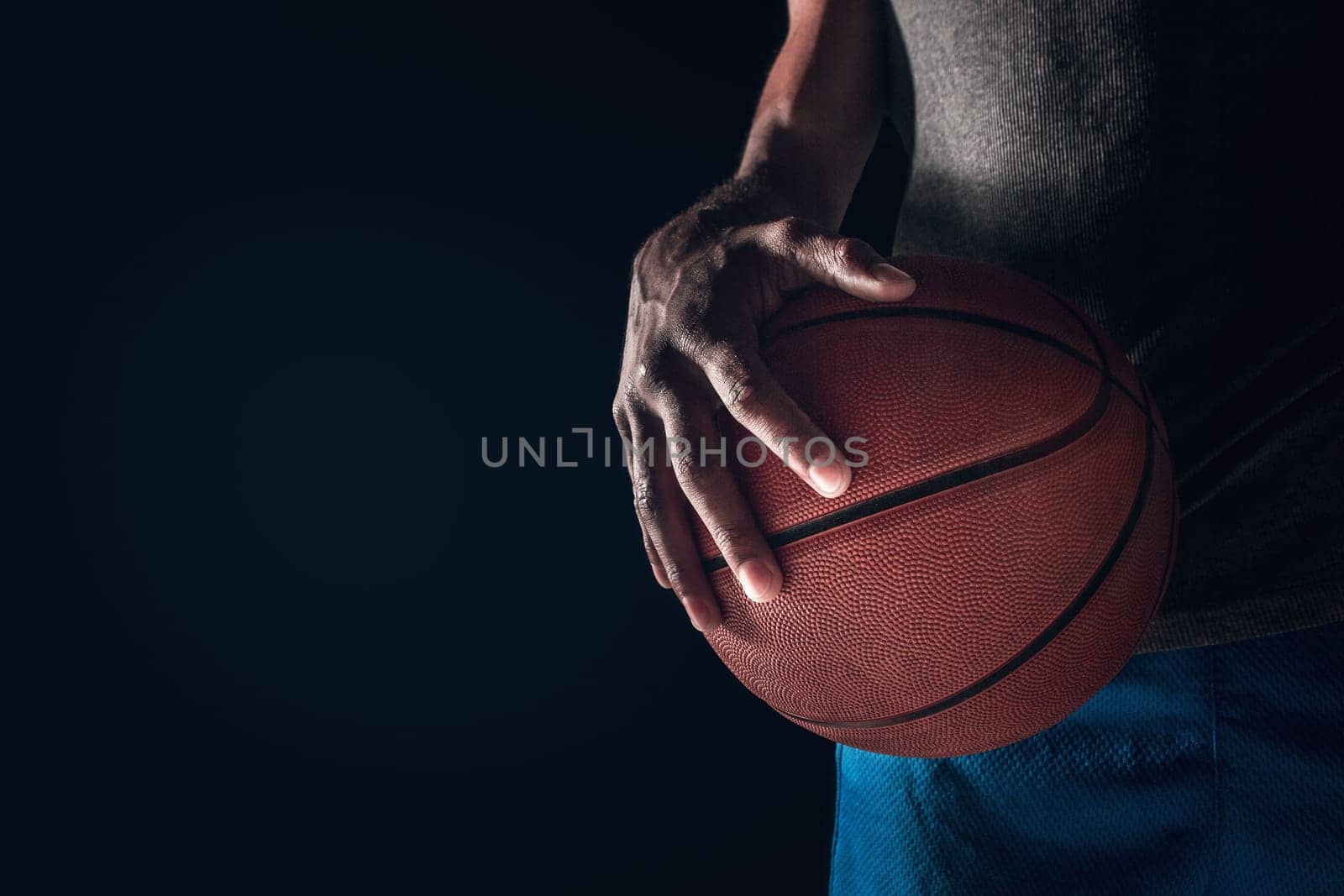 The hands of a basketball player with a ball against dark studio background. advertising concept