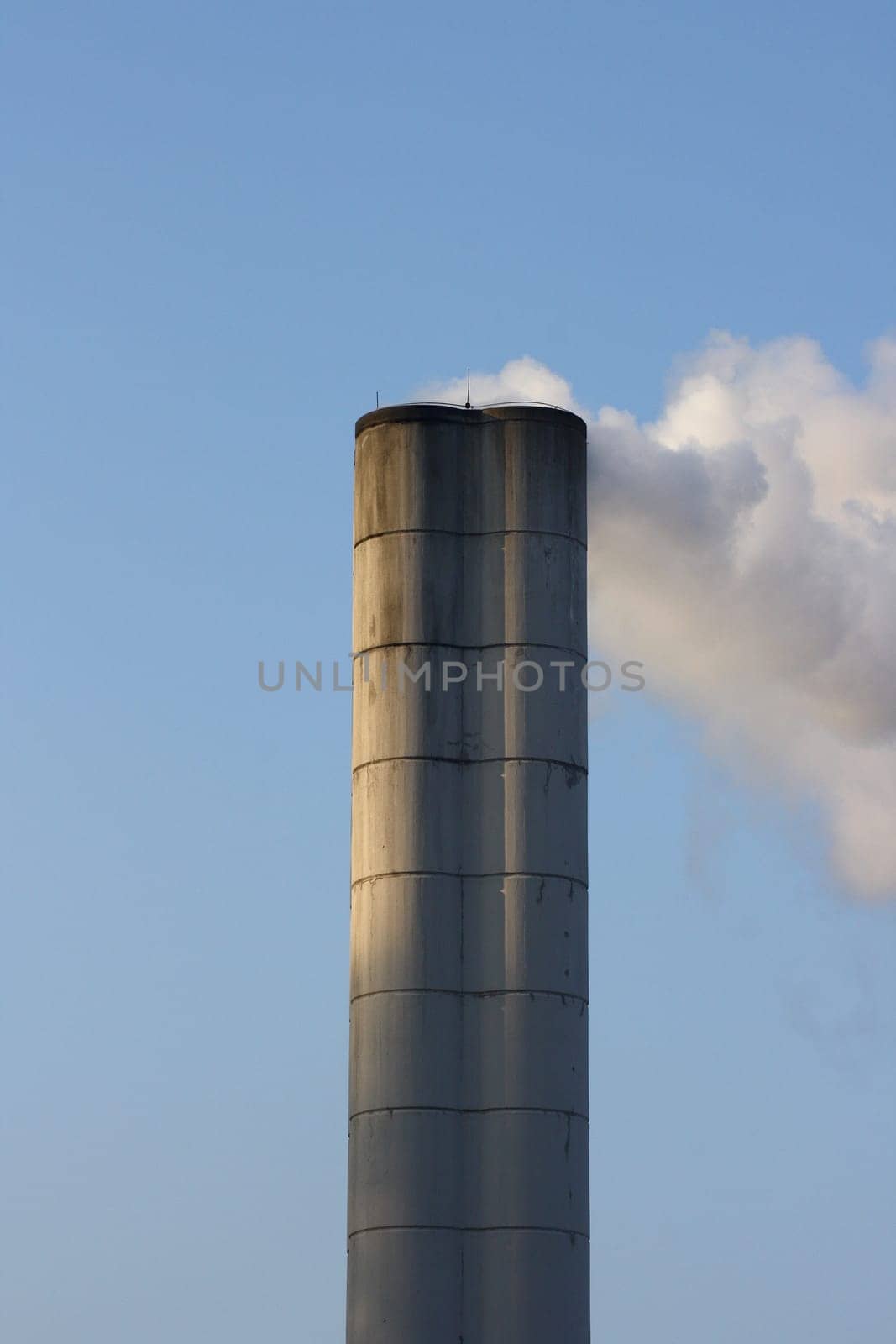 Large chimney sent clouds of steam into the blue sky