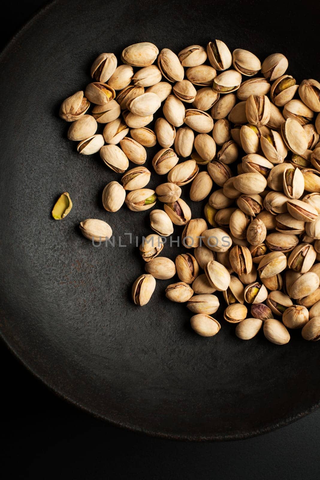 Bowl with pistachios on a black table background