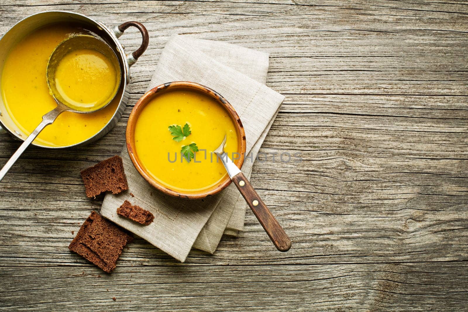 Healthy vegetable cream soup with bread on wooden background