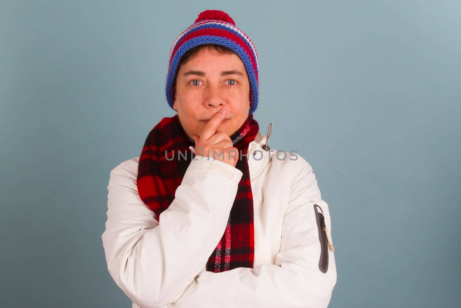 Middle-aged woman in winter clothes puts fingers on her mouth