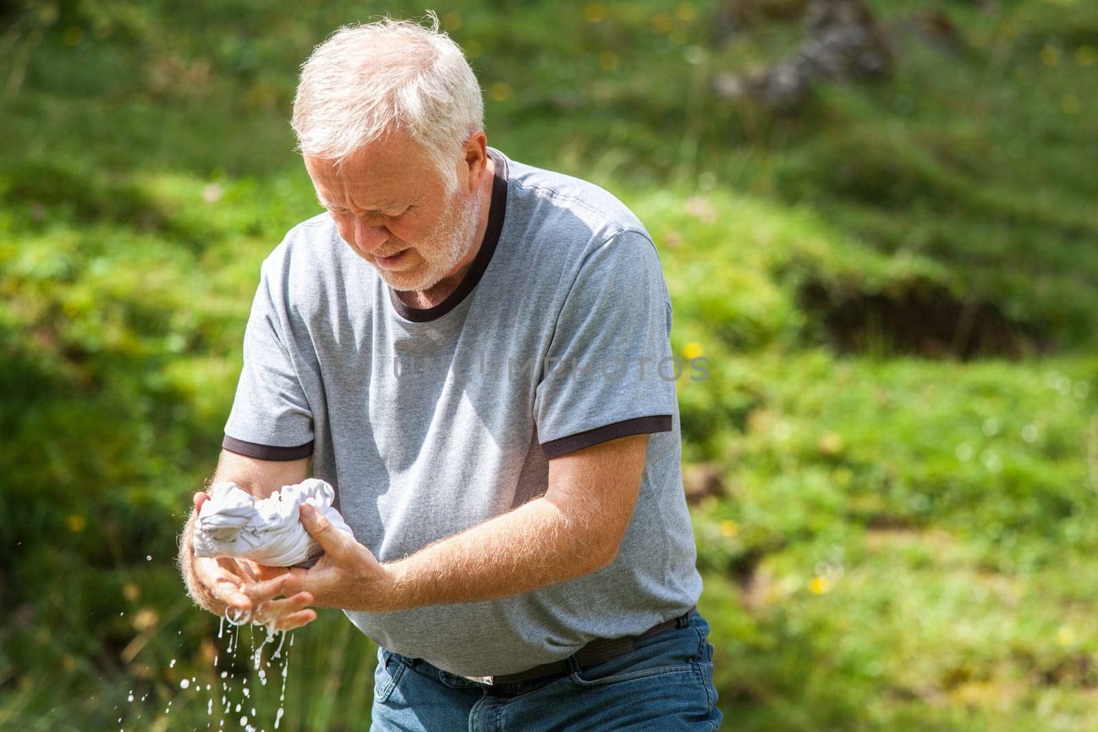 Old man pressing his own laundry in the middle of nature