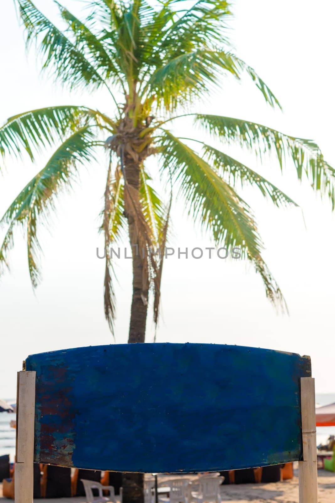 Blank blue vintage signboard with copy space and palm tree in background. Vacation and travel concept