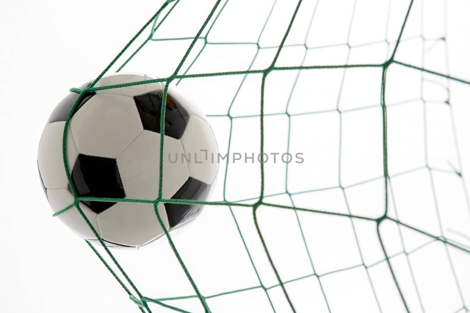 soccer ball in green goal in front of white background