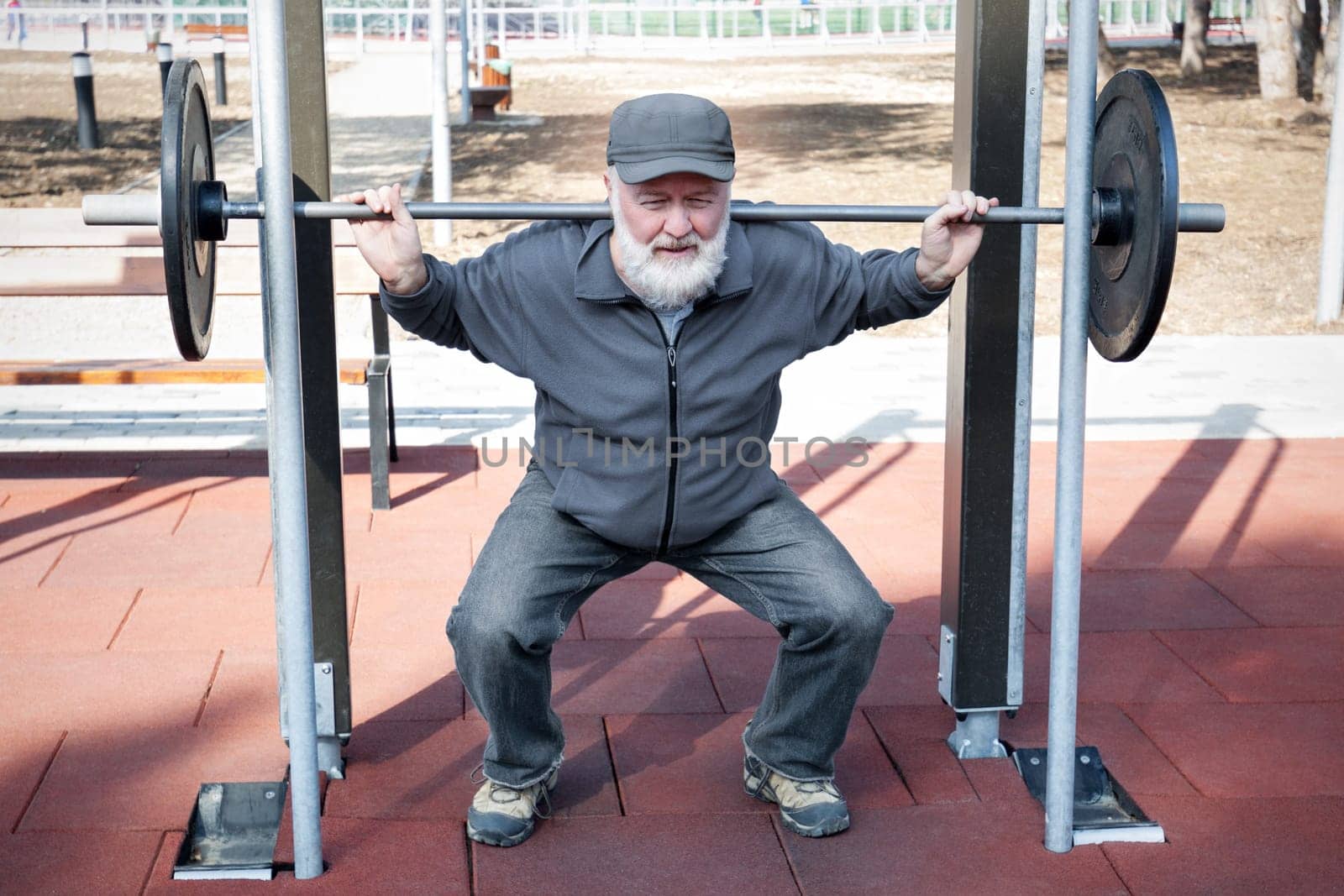 An old man lifting weights in the fitness park.