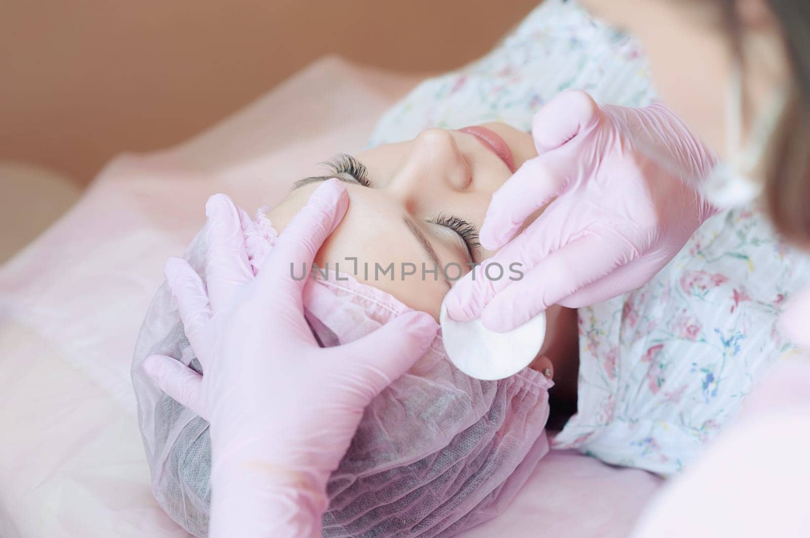 A young woman lies and gets a make-up of her eyebrows in a beauty salon. The use of permanent makeup on the eyebrows. The master works with the eyebrows. Semi-permanent makeup.