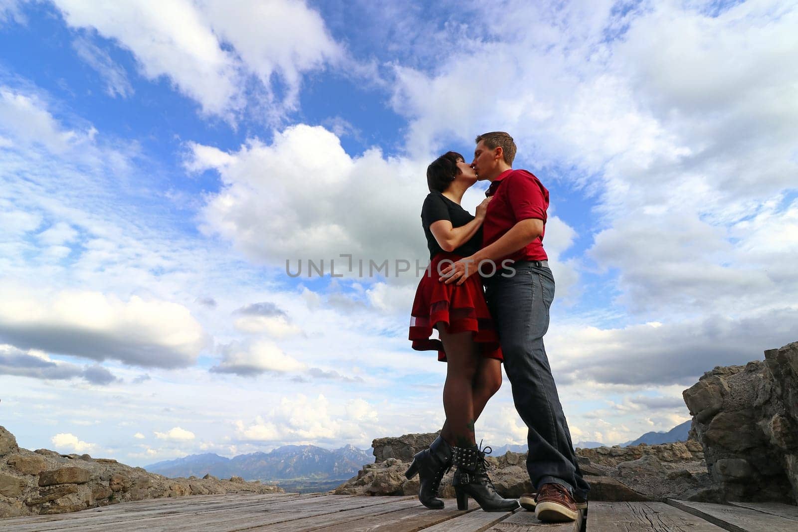 Heavenly feelings for a couple of lovers. A kissing couple in front of a cloudy sky